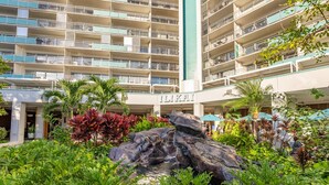 A multi-story hotel with balconies, a rock garden, and lush greenery. - @ Marbella Lane – Dreamy Sunset Views by the Sea (Honolulu)