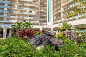 A multi-story hotel with balconies, a rock garden, and lush greenery. - @ Marbella Lane – Dreamy Sunset Views by the Sea (Honolulu)