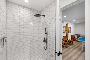 A modern bathroom with white subway tiles, a shower with a handheld showerhead, and a visible toilet. - 502 Colony Street (Melbourne Beach)