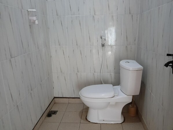 Un baño pequeño con azulejos blancos, un inodoro y un bidé.