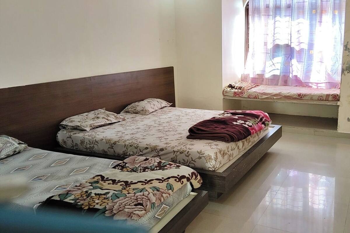 Un dormitorio con dos camas, una ventana con cortinas y piso de baldosas.