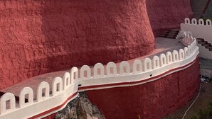 Un edificio de varios pisos con fachada roja y blanca, que presenta una pared de piedra y una cerca de piquetes blancos.