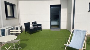 A patio with artificial grass, a table, two chairs, a sofa, and a single lounge chair. - On the road to the castles (Soussans)
