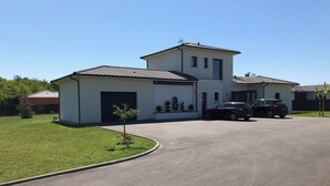 A two-story house with a garage, a driveway, and two parked cars. - On the road to the castles (Soussans)