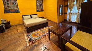 Un dormitorio con cama, piso de madera, una mesita y una silla.