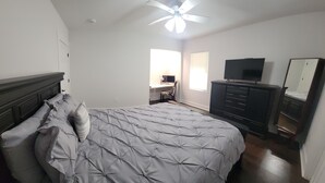 A bedroom with a bed, a dresser, a television, and a desk with a chair. - Newly renovated home near TMC, Downtown, UH, TSU available for short term rental (Houston)