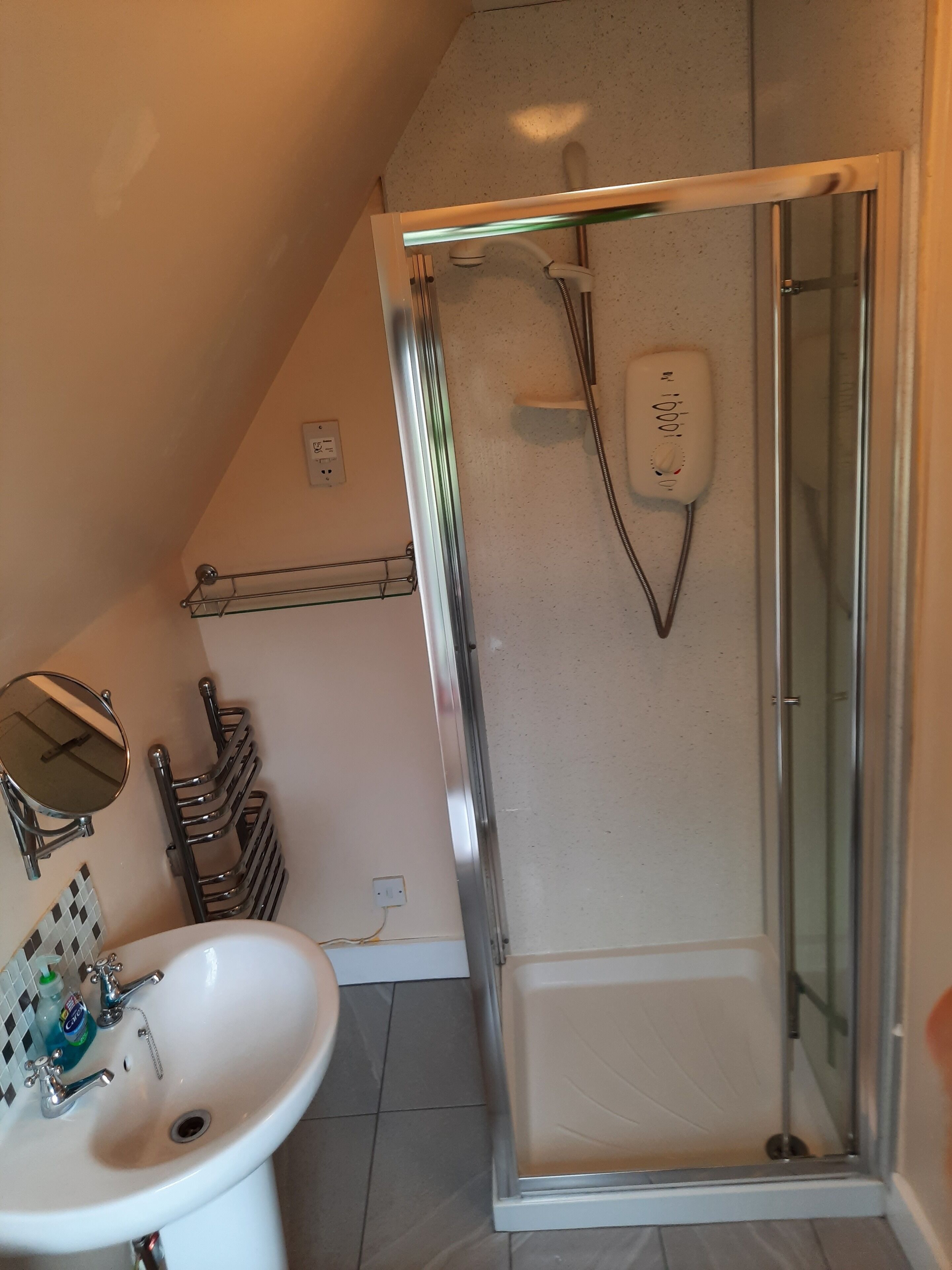 A bathroom with a white sink, a glass shower enclosure, and a towel rack.