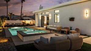 A modern outdoor living area with a pool, seating, and a view of the mountains. - Desert Oasis: Pool, Spa, Golf Sim & Family Fun! (Bermuda Dunes)