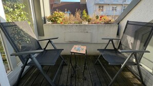 A balcony with two chairs and a small table, overlooking a garden and buildings. - Lovely 3BR Apt With Balcony Rennweg (Vienna)