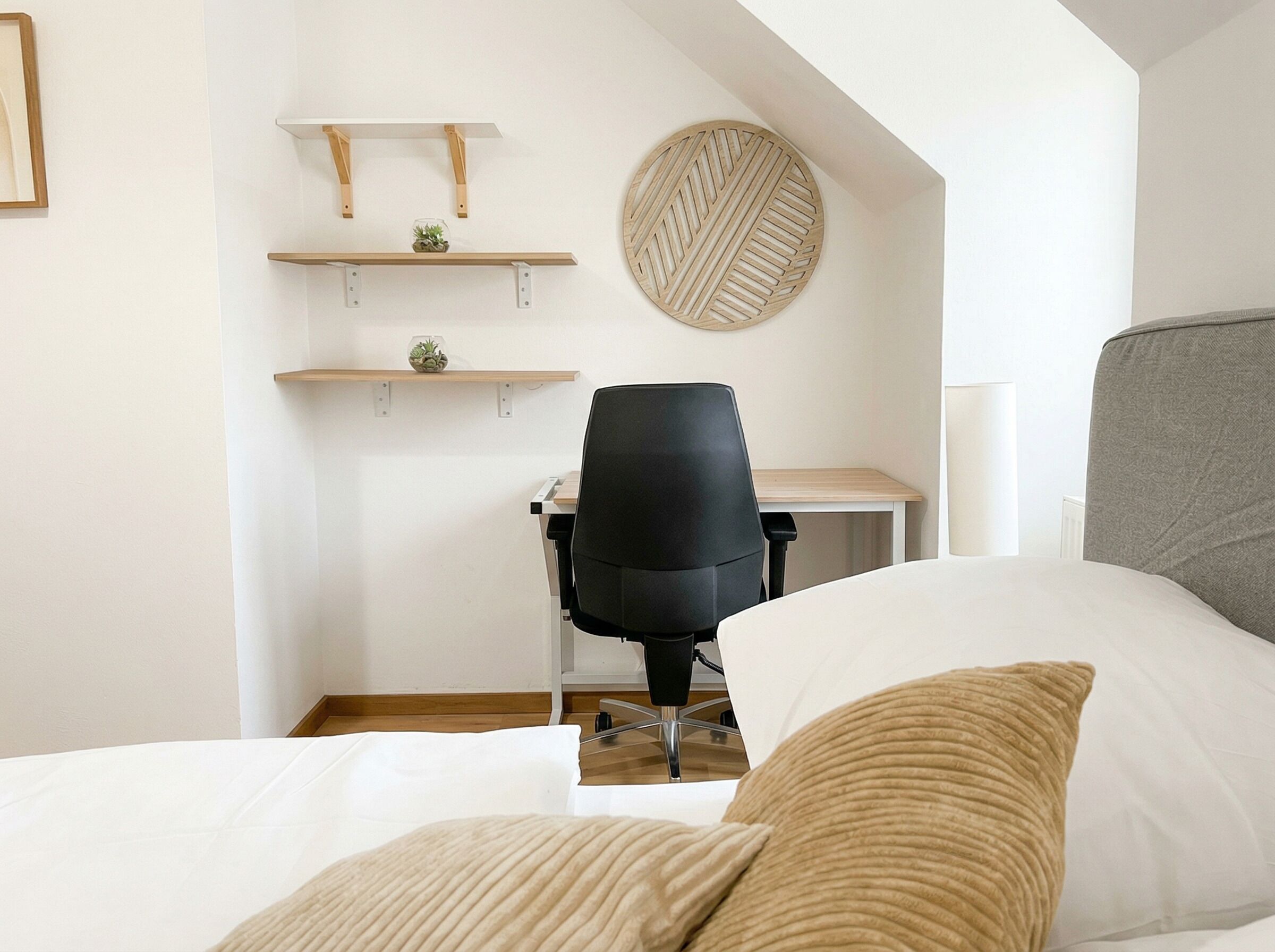 Ein Schlafzimmer mit Bett, Schreibtisch, Stuhl und Pflanzenregalen.