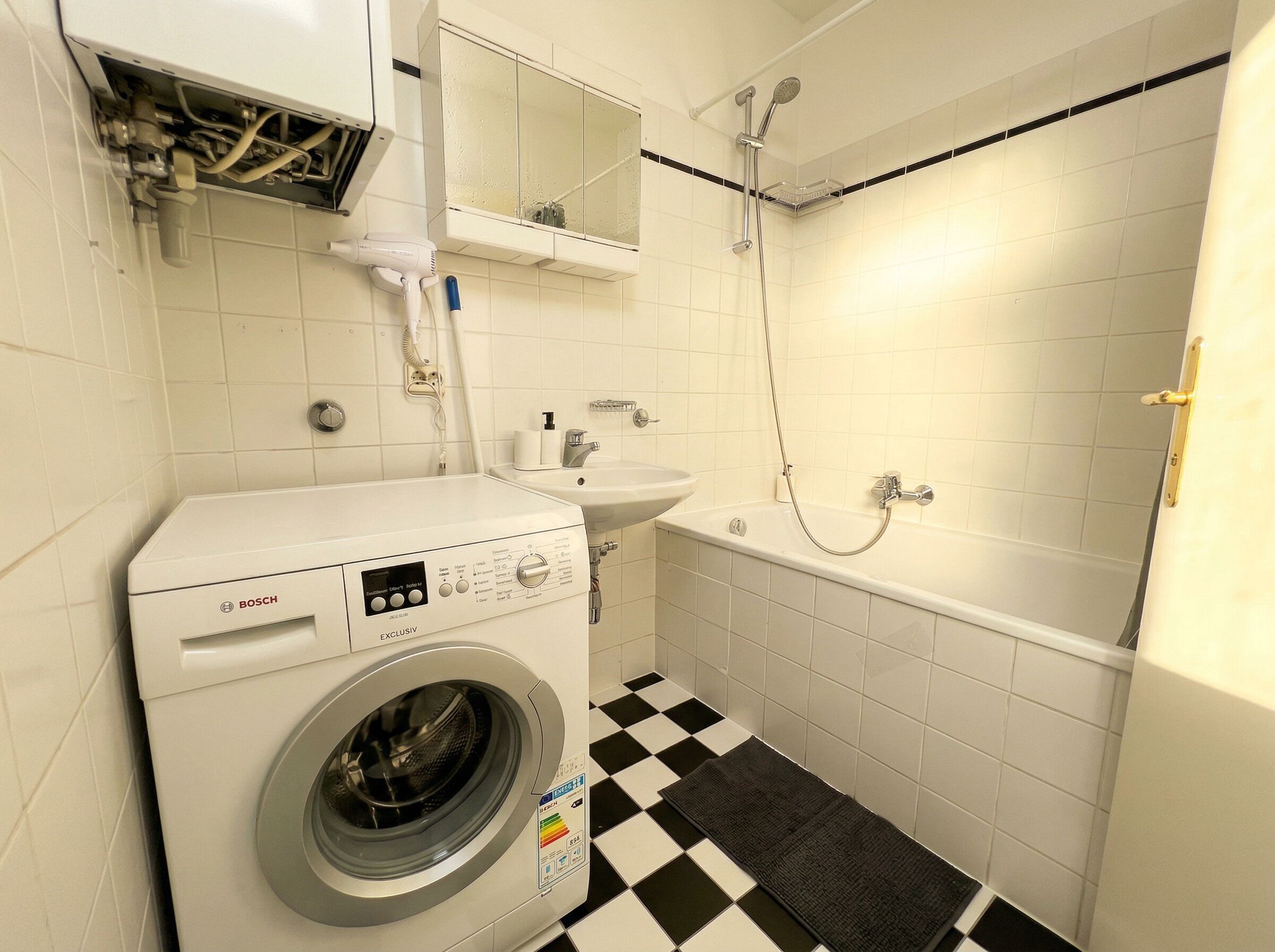 A compact bathroom with a Bosch washing machine, a sink, and a shower.