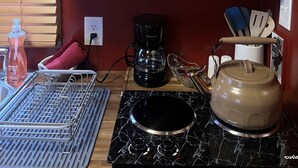 A compact kitchen with wooden cabinets, a coffee maker, a kettle, and various kitchen utensils.