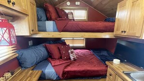A compact, well-organized cabin with two bunk beds, a small kitchenette, and a window providing natural light.
