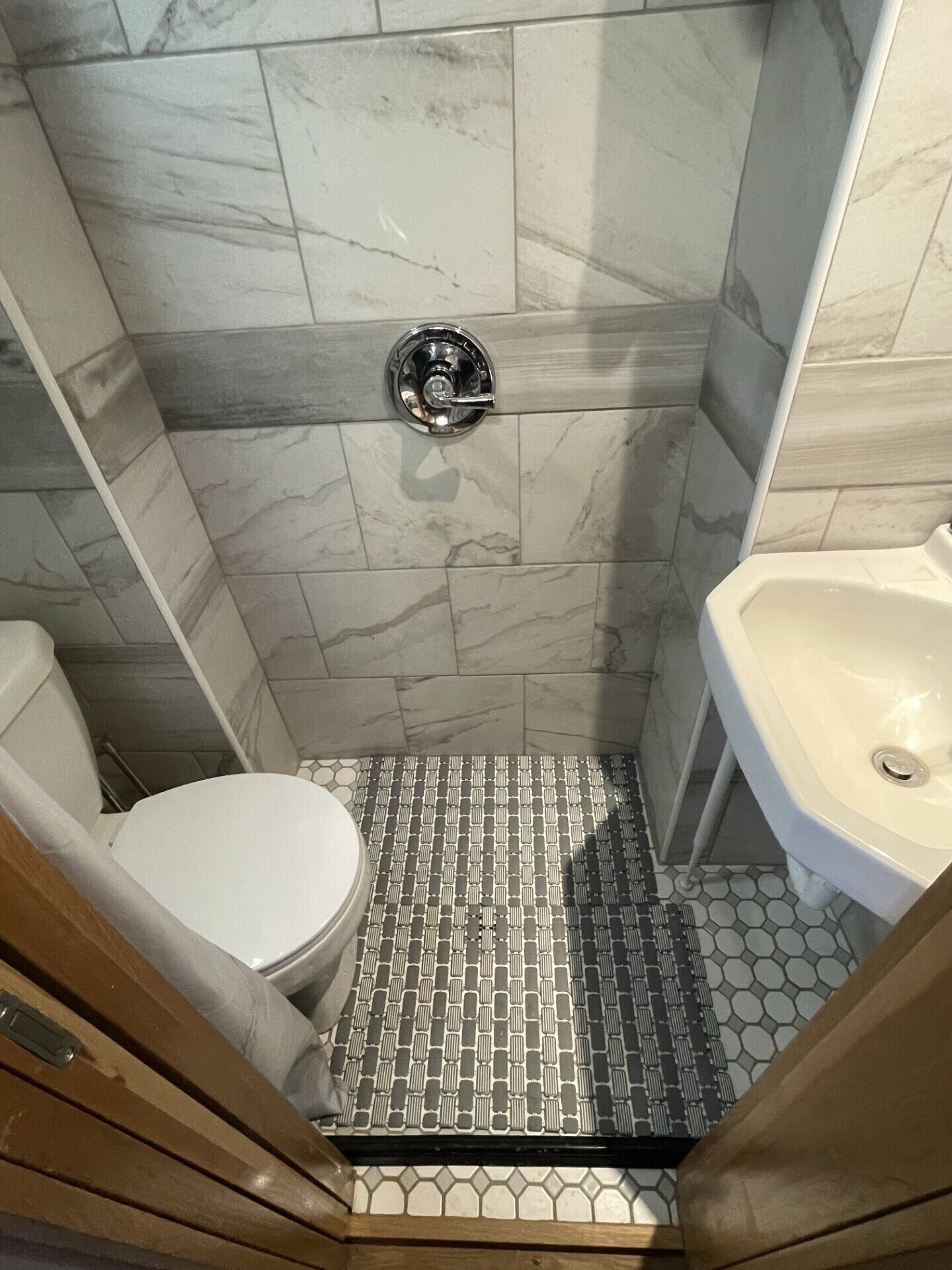 A bathroom with a toilet, a sink, and a shower. The floor has a patterned tile design.