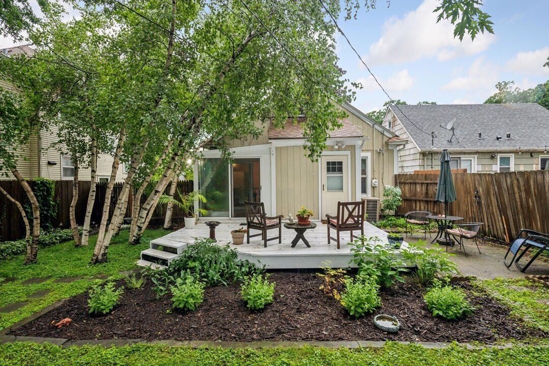 Un jardin avec une terrasse, des chaises et une clôture en bois.