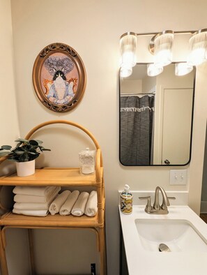 A bathroom with a sink, mirror, towel rack, and decorative items. - Elegant Linden Hills Home, Family Friendly, Walk to Lake, Dining, and Shopping (Minneapolis)