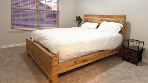 Una camera da letto con un letto in legno, biancheria bianca, un piccolo comodino e una finestra con persiane.