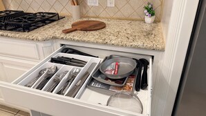 Una cucina con piano di lavoro in granito, tagliere in legno, scaffale per spezie e cassetto con utensili.