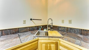 A bathroom with a granite countertop, a sink with a faucet, and a wooden vanity.