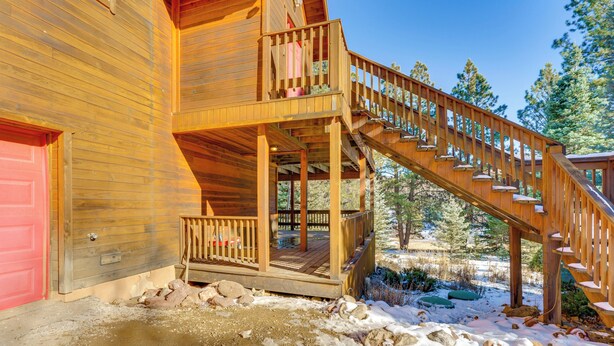 A wooden cabin with a red door, a wooden staircase, and a deck.