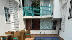 A rectangular swimming pool with clear blue water, surrounded by wooden decking and wicker furniture. - High Five Hotels (Assagao)