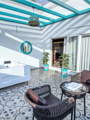 A sunlit outdoor area with a white bathtub, wicker furniture, and potted plants. - High Five Hotels (Assagao)