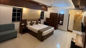 A modern bedroom with a large bed, a sofa, a vanity, and a ceiling fan. - High Five Hotels (Assagao)