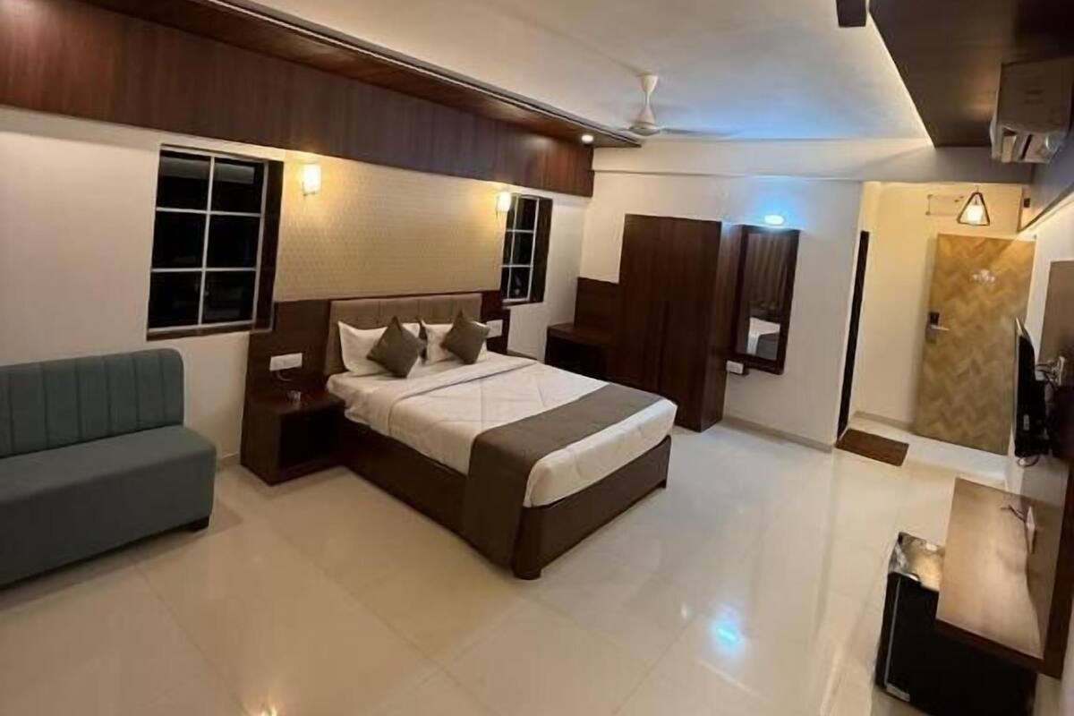 A modern bedroom with a large bed, a sofa, a vanity, and a ceiling fan.