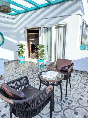 Un patio con mobili in vimini, piante in vaso e pavimento decorato.