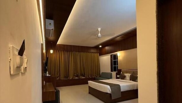 A modern hotel room with a large bed, a smaller seating area, a ceiling fan, and a view of the outdoors. - High Five Hotels (Assagao)