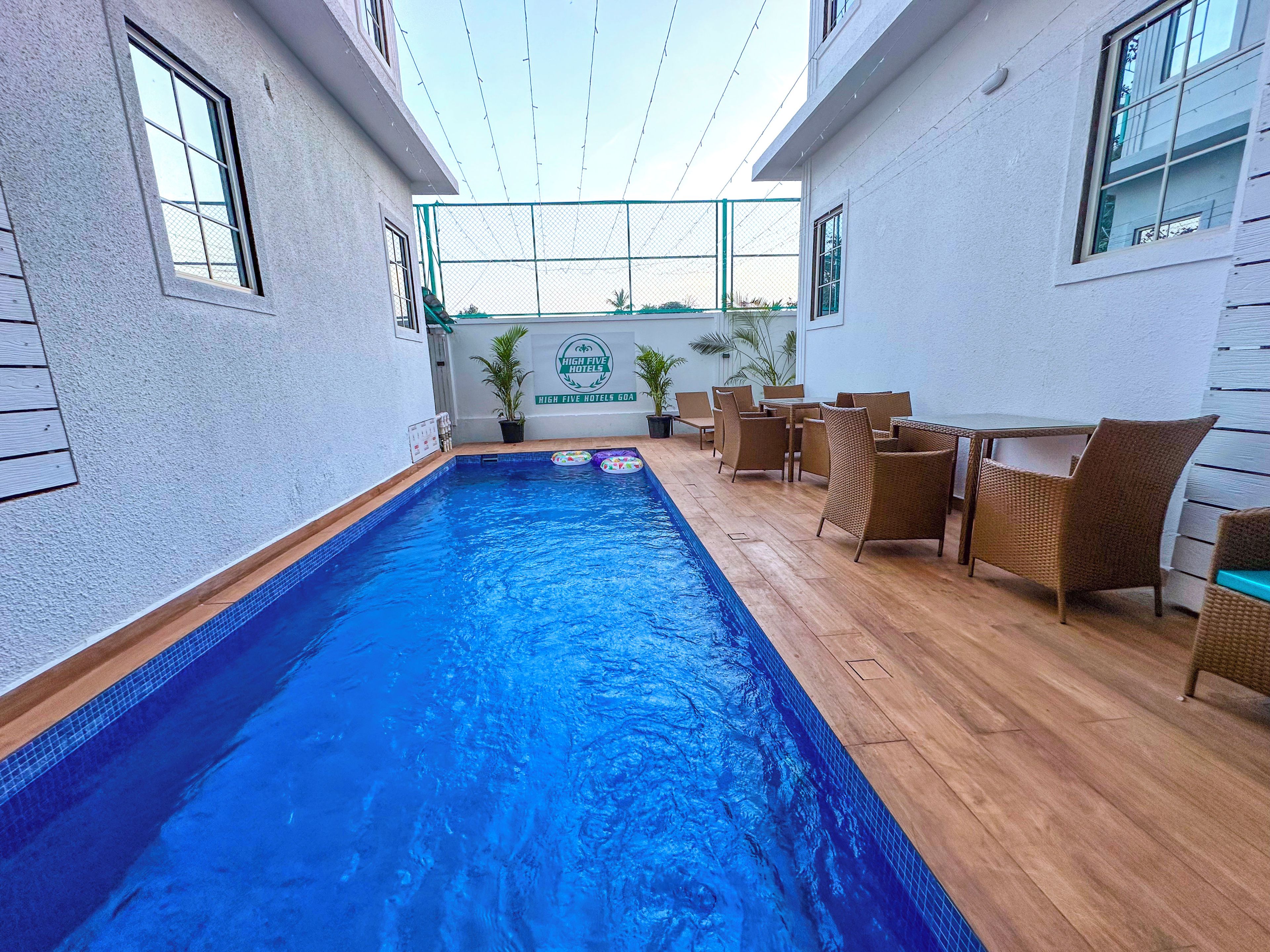 Una piscina interior con una terraza de madera, muebles de mimbre y un letrero de High Five Hotels.