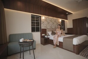 A modern bedroom with a bed, a small table with a cup and plate, a sofa, and a nightstand. - High Five Hotels (Assagao)