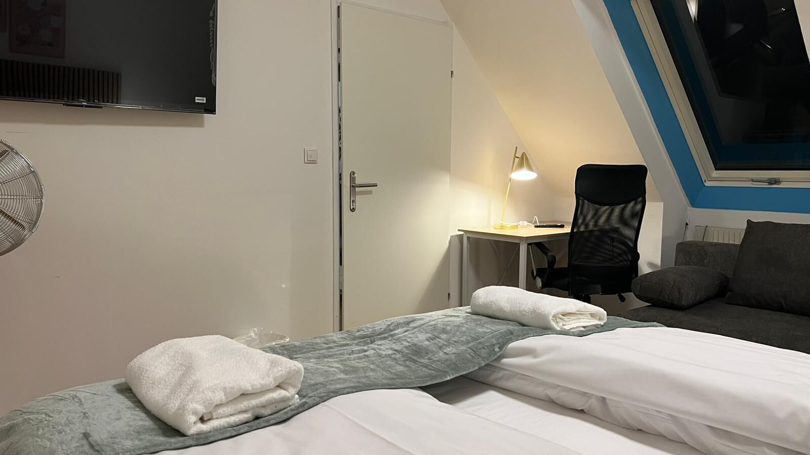 Een slaapkamer met een bed, een bureau, een stoel, een televisie en een raam.