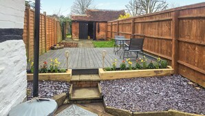 A backyard with a patio, a small garden, and a wooden fence. - 1 bedroom accommodation in Aston Cantlow, near Stratford-upon-Avon (Aston Cantlow, near Stratford-upon-Avon)