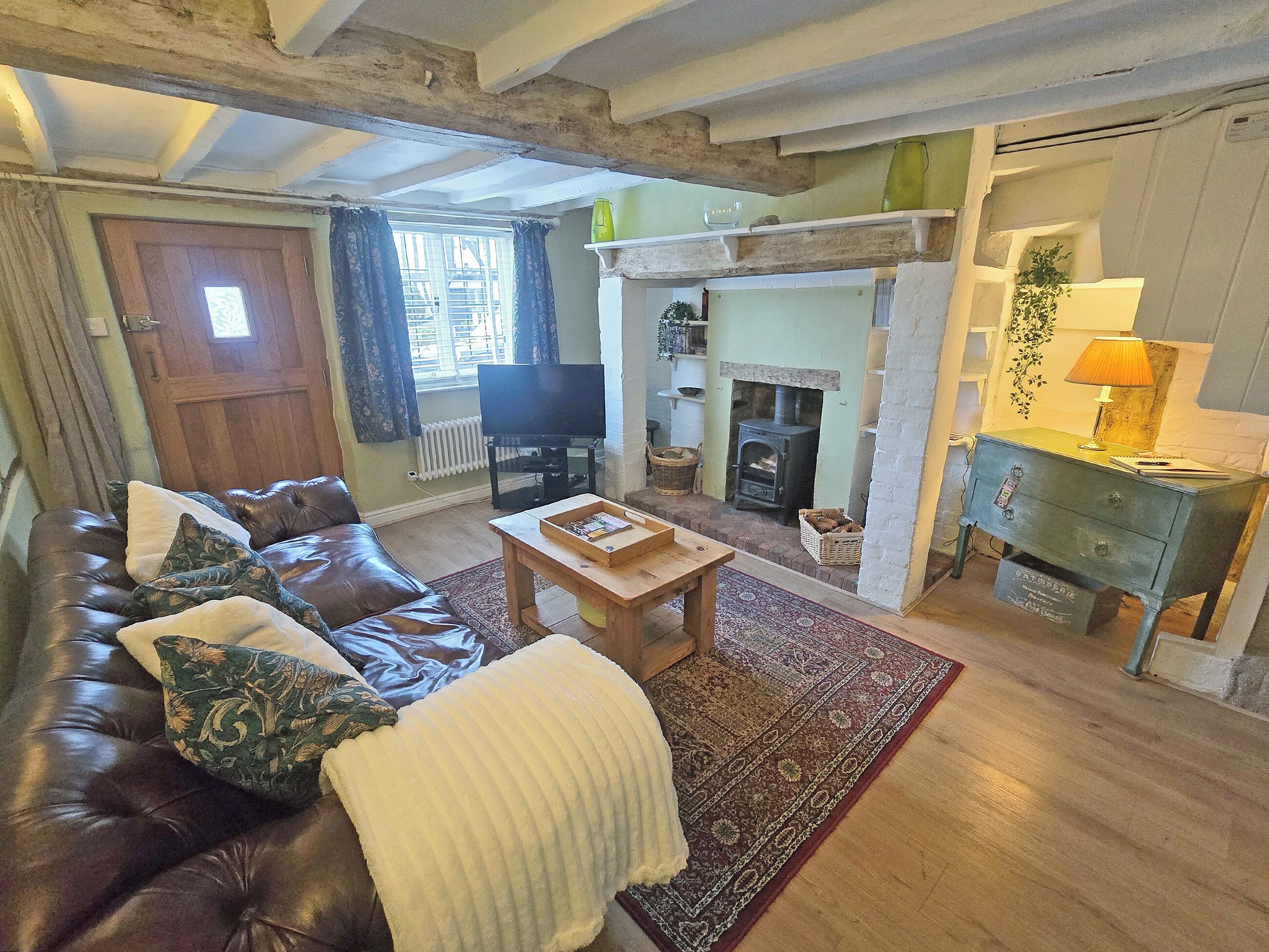 A living room with a leather sofa, a wooden coffee table, a fireplace, and a television.