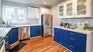 Eine moderne Küche mit blauen Schränken, einem Edelstahlkühlschrank und einer weißen Arbeitsplatte.