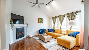 Ein modernes Wohnzimmer mit Kamin, einer Couch und einem Fernseher.