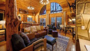 Interior acogedor de una cabaña con detalles de madera, un gran tronco de árbol, un sofá y un comedor.