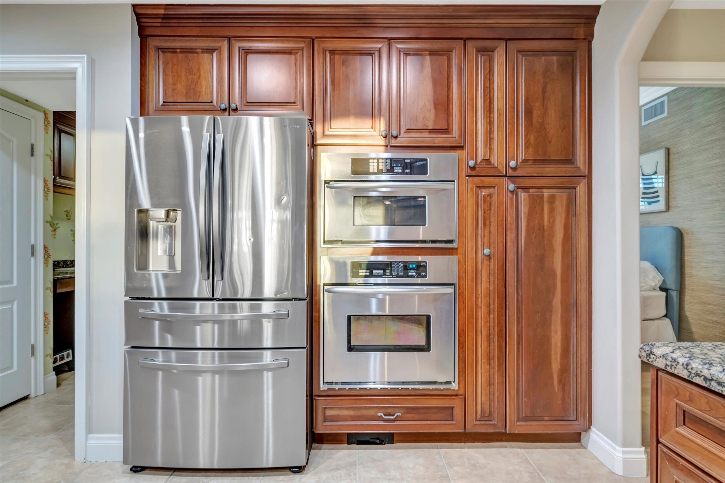 Una cocina con un refrigerador de acero inoxidable, un horno empotrado y armarios de madera.