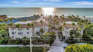 A coastal hotel with multiple buildings, palm trees, and a view of the ocean. - Holmes Beachfront Oasis (Holmes Beach)