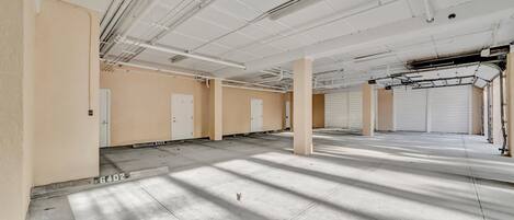 A spacious indoor area with concrete floors, beige walls, and white ceilings with exposed pipes.