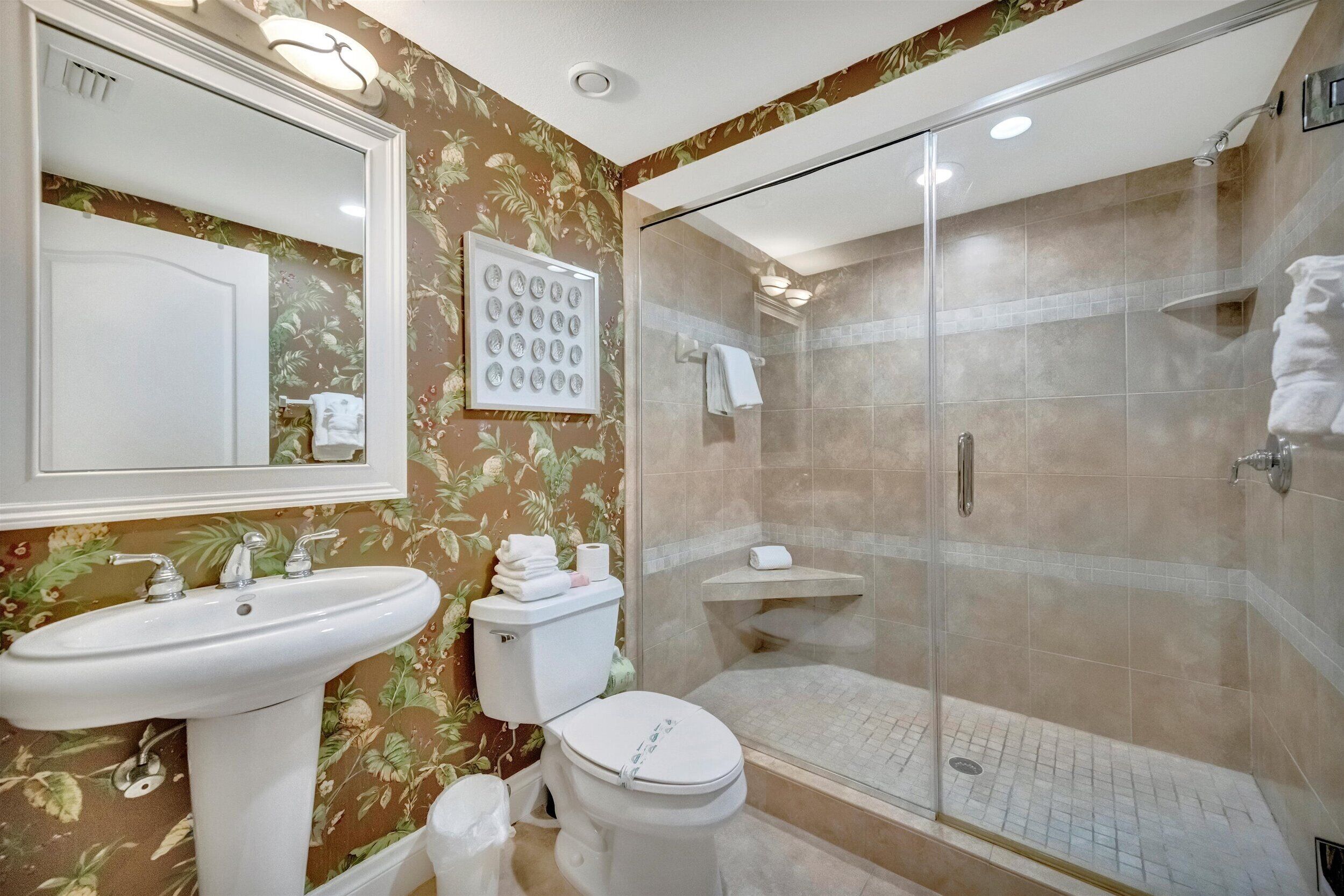 A bathroom with a sink, toilet, and glass-enclosed shower.