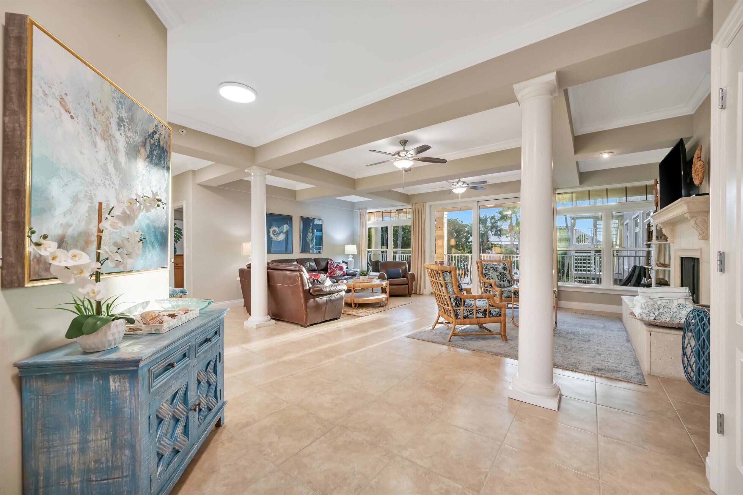 A spacious living area with a large painting, a blue cabinet, and a ceiling fan.
