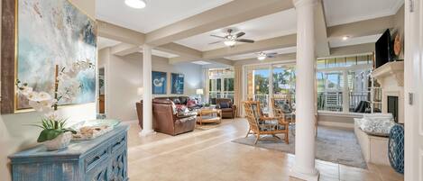 A spacious living area with a large painting, a blue cabinet, and a ceiling fan.