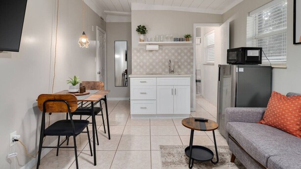 En kompakt opholdsstue med spiseplads, tekøkken og siddeområde.