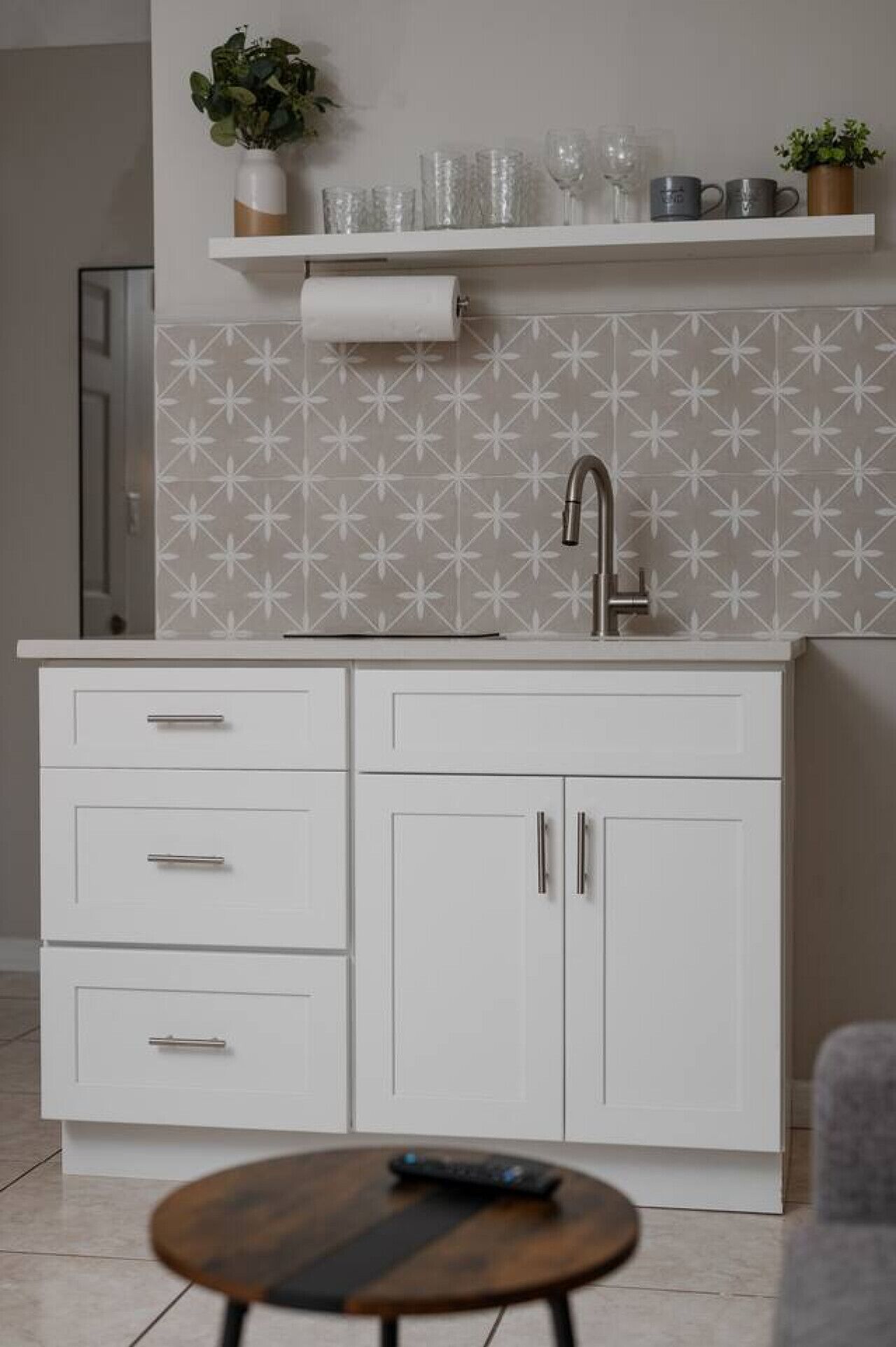 A modern kitchen with white cabinets, a stainless steel sink, and a patterned backsplash.