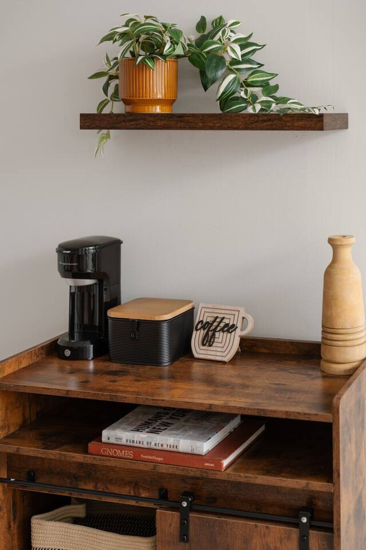 A wooden shelf with a coffee maker, a wooden mug, and a book titled 'Humans of New York'.