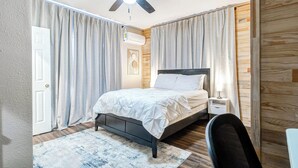 A bedroom with a bed, a nightstand, a chair, a ceiling fan, and a window with curtains. - Houston Private Retreat, 17 min Downtown (Houston)