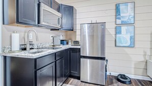A modern kitchen with dark cabinets, stainless steel appliances, a marble countertop, and two abstract paintings on the wall. - Houston Private Retreat, 17 min Downtown (Houston)