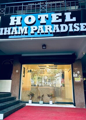La entrada al Hotel Sham Paradise, con alfombra roja y plantas en macetas.